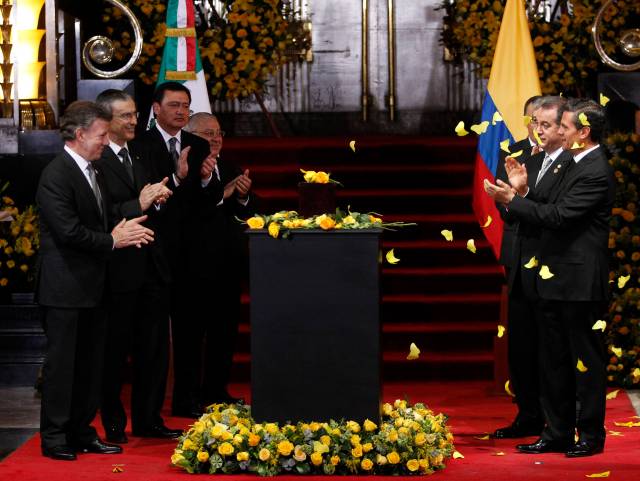 Colombia's President Juan Manuel Santos and his Mexican counterpart Enrique Pena Nieto applaud while standing next to an urn containing the ashes of late Colombian Nobel laureate Gabriel Garcia Marquez in Mexico City