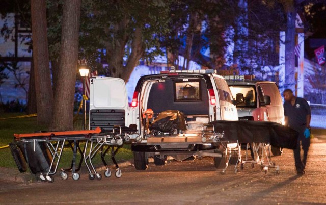 A Harris County Medical Examiner prepares to place a body into the coroner's van as they remove bodies from a home after several people were shot to death, in the Houston suburb of Spring, in Texas