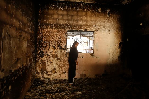A Palestinian woman inspects her burnt house after retuning to Beit Hanoun town in the northern Gaza Strip