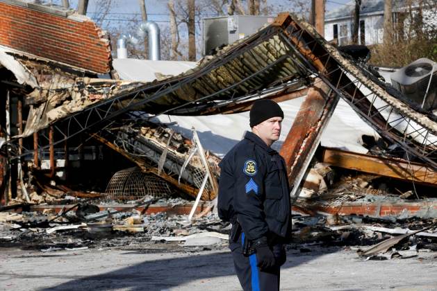 Un oficial de policía ve el sitio de un edificio que fue incendiado en los disturbios de la noche anterior en Ferguson , Missouri 25 de noviembre de 2014. En St. Louis se preparó para otra jornada de protestas el martes, luego que jurado libró de los cargo a un policía blanco de la muerte a tiros de un adolescente negro desarmado , lo que desató una noche de violentos disturbios y cargada de racismo. REUTERS / Jim Young