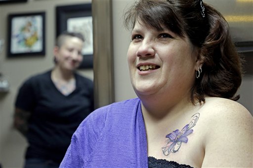 Foto: la tatuadora Ashley Neumann (izquierda), observa a la sobreviviente de cáncer de mama Mari Jankowski sonriendo mientras habla de su nuevo tatuaje, en West Allis, Wisconsin. / AP