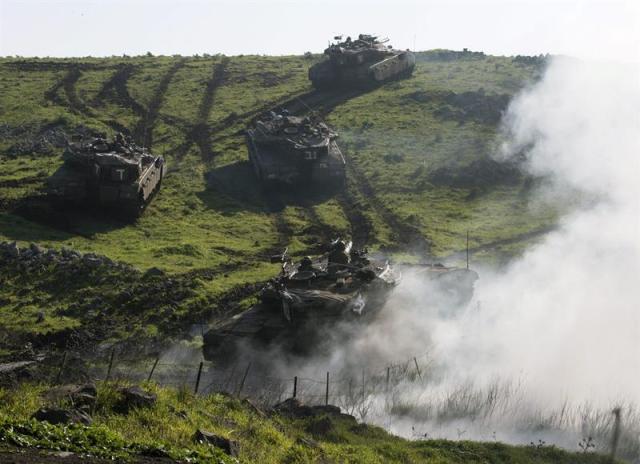 Un tanque israelí produce una nube de humo para cubrir los movimientos de sus compañeros durante unas maniobras con fuego real en Altos del Golán, hoy, martes 20 de enero de 2015. El Ejército israelí ha elevado el nivel de alerta en el norte del país ante el temor de una represalia por parte de Hizbulá al ataque atribuido a Israel el domingo en suelo sirio, en el que murió un responsable el grupo chií libanés. Dos bombardeos aéreos acabaron con la vida de Yihad Mugniye, un responsable de Hizbulá y de otros cinco milicianos del grupo chií en territorio sirio. La alerta está vigente en varios puestos situados a lo largo de las divisorias con Líbano y Siria. EFE/Jim Hollander