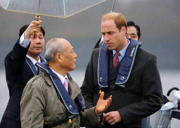 Britain's Prince William, Duke of Cambridge, listens as Tokyo Governor Yoichi Masuzoe speaks on the deck of a cruise boat during a tour of the Tokyo Bay area in Tokyo