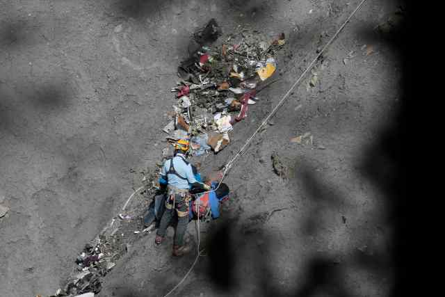 A French rescue worker inspects the debris from the Germanwings Airbus A320 at the site of the crash, near Seyne-les-Alpes, French Alps