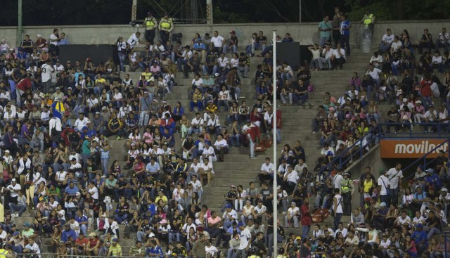 Aficionados al béisbol observan el juego entre los Leones de Caracas y los Navegantes del Magallanes en Caracas, Venezuela. Los más arraigados seguidores del béisbol, que celebran lo que los aficionados venezolanos llaman la religión nacional, ocuparon menos de la mitad del estadio luego de un incremento de más del 300% al precio de las entradas. (Foto AP/Ariana Cubillos)