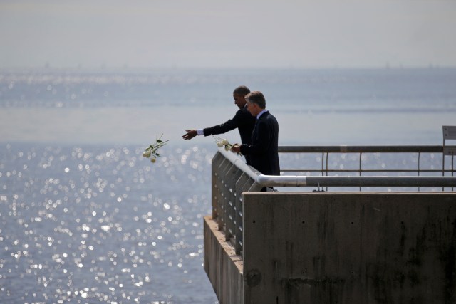 U.S. President Barack Obama throws flowers in the River Plate while visiting with Argentina's President Mauricio Macri (R) the Parque de la Memoria (Remembrance Park) where they honored victims of Argentina's Dirty War on the 40th anniversary of the 1976 coup that initiated that period of military rule, in Buenos Aires, March 24, 2016. REUTERS/Carlos Barria TPX IMAGES OF THE DAY