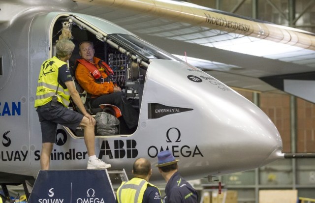 Solar Impulse 2 pilot Andre Borschberg, in the orange jacket, gets strapped into the cockpit before taking his first training flight in the airplane at Kalaeloa Airport, in Kapolei, Hawaii on March 31, 2016.  Solar impulse 2 is attempting to be the first solar powered airplane to fly around the world without using fuel.  / AFP / Eugene Tanner