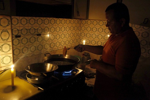 Un hombre cocina a la luz de las velas en San Cristóbal. Foto: REUTERS/Carlos Eduardo Ramirez