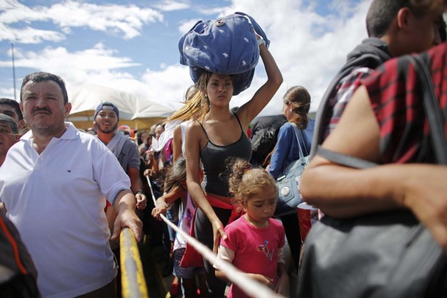 En esta imagen del domingo 17 de julio de 2016, una mujer carga una bolsa sobre la cabeza mientras espera en una fila para cruzar la frontera a Colombia a través del puente Simón Bolívar en San Antonio del Tachira, Venezuela. Decenas de miles de venezolanos cruzaron la frontera a Colombia el domingo para buscar comida y medicinas que escasean en casa. Es el segundo fin de semana seguido en que el gobierno de Venezuela abre el paso que conecta los dos países. (AP Foto/Ariana Cubillos)