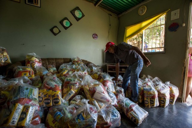 ACOMPAÑA CRÓNICA: VENEZUELA ALIMENTOS - CAR01. CARACAS (VENEZUELA), 28/08/2016.- Fotografía del 20 de agosto del 2016, donde se observan un operativo de entrega de bolsas de comida a habitantes de un barrio del km 3 del Junquito por parte Comités Locales de Abastecimiento y Producción (CLAP) en Caracas (Venezuela). La severa escasez de productos básicos en Venezuela ha llevado a que la foto diaria del país sea una inmensa fila frente a muchos abastos y supermercados, un problema que el Gobierno intenta solucionar con un sistema de venta de alimentos, conformado solo por militantes chavistas, conocido como CLAP. EFE/MIGUEL GUTIÉRREZ