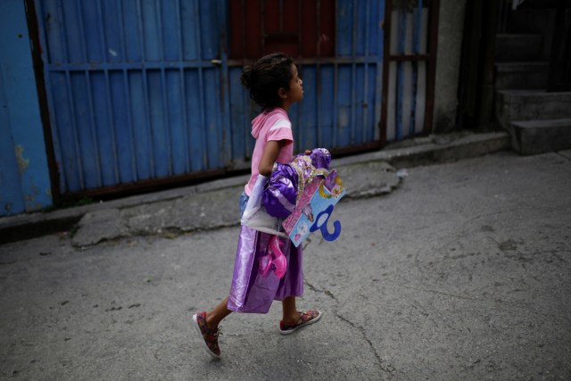 A girl walks with a costume received during a toy distribution program with Miguel Pizarro, deputy of the Venezuelan coalition of opposition parties (MUD), at the slum of Petare in Caracas, Venezuela December 20, 2016. Picture taken December 20, 2016. REUTERS/Marco Bello