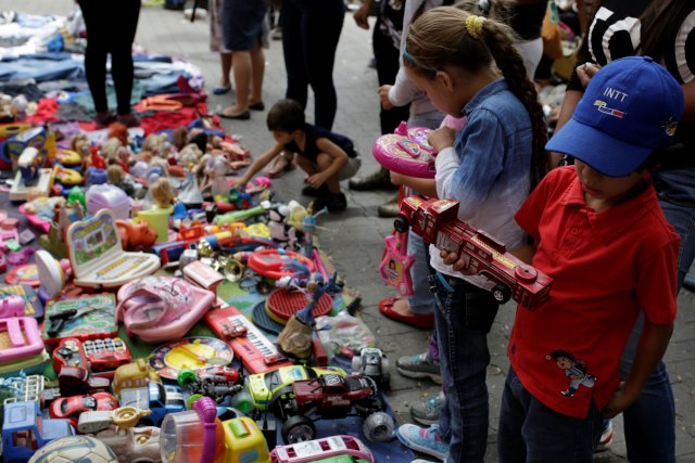 Children look at second-hand toys at a street market in the slum of Catia in Caracas, Venezuela December 21, 2016. Picture taken December 21, 2016. REUTERS/Marco Bello