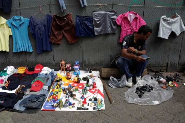 A vendor sits next to second-hand toys and clothes at a street market in the slum of Catia in Caracas, Venezuela December 21, 2016. Picture taken December 21, 2016. REUTERS/Marco Bello