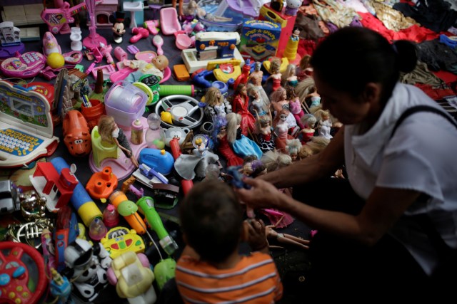 People look at second-hand toys at a street market in the slum of Catia in Caracas, Venezuela December 21, 2016. Picture taken December 21, 2016. REUTERS/Marco Bello