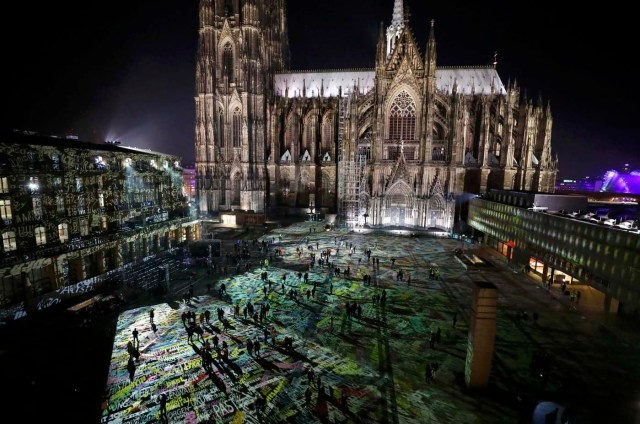 People walk over the laser installation "Time Drifts Cologne" before New Year celebrations for 2017 in Cologne, Germany, December 31, 2016. REUTERS/Wolfgang Rattay