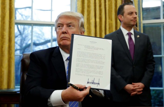 U.S. President Donald Trump holds up the executive order on the reinstatement of the Mexico City Policy after signing in the Oval Office of the White House in Washington January 23, 2017. At his side is White House Chief of Staff Reince Priebus.  REUTERS/Kevin Lamarque