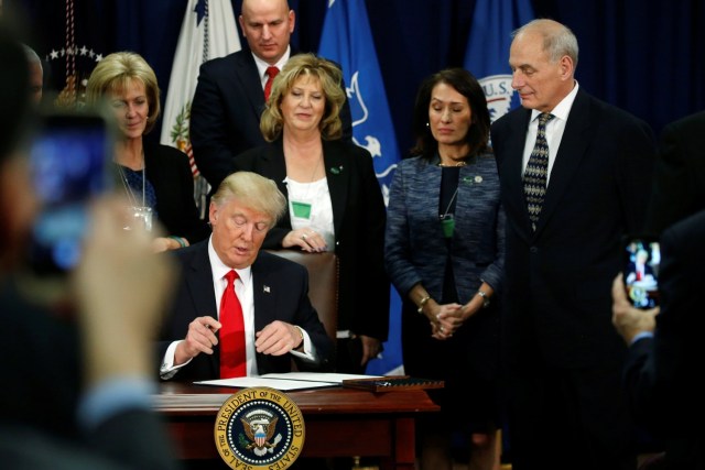 U.S. Homeland Security Secretary John Kelly (R) looks on as U.S. President Donald Trump signs an executive order at Homeland Security headquarters in Washington, U.S., January 25, 2017.  REUTERS/Jonathan Ernst