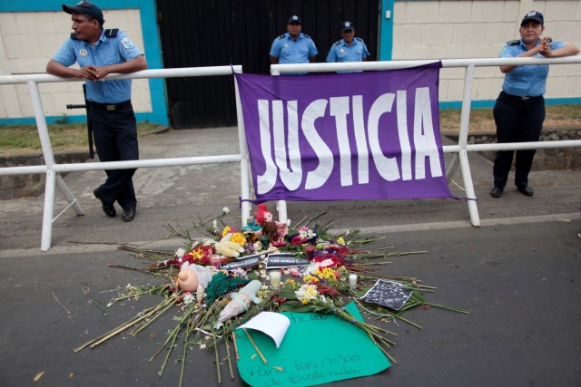 Police officers stand guard outside Guatemala's embassy in Managua as activist place flowers and stuffed toys during a protest to demand justice for the victims of a fire at the Virgen de Asuncion children shelter in Guatemala, in Managua, Nicaragua March 16, 2017. REUTERS/Oswaldo Rivas