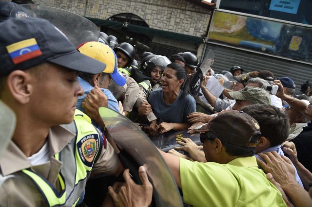 Opposition activists confront riot police during a protest against the government in Caracas on May 12, 2017. Daily clashes between demonstrators -who blame elected President Nicolas Maduro for an economic crisis that has caused food shortage- and security forces have left 38 people dead since April 1. Protesters demand early elections, accusing Maduro of repressing protesters and trying to install a dictatorship. / AFP PHOTO / JUAN BARRETO