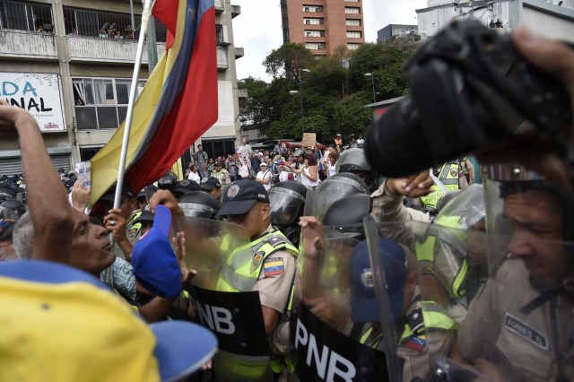Opposition activists clash with riot police during a protest against the government in Caracas on May 12, 2017. Daily clashes between demonstrators -who blame elected President Nicolas Maduro for an economic crisis that has caused food shortage- and security forces have left 38 people dead since April 1. Protesters demand early elections, accusing Maduro of repressing protesters and trying to install a dictatorship. / AFP PHOTO / JUAN BARRETO
