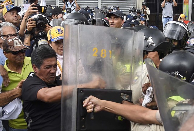 Opposition activists confront riot police during a protest against the government in Caracas on May 12, 2017. Daily clashes between demonstrators -who blame elected President Nicolas Maduro for an economic crisis that has caused food shortage- and security forces have left 38 people dead since April 1. Protesters demand early elections, accusing Maduro of repressing protesters and trying to install a dictatorship. / AFP PHOTO / JUAN BARRETO / ALTERNATIVE CROP