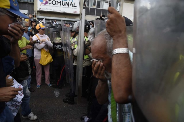 Opposition activists confront riot police during a protest against the government in Caracas on May 12, 2017. Daily clashes between demonstrators -who blame elected President Nicolas Maduro for an economic crisis that has caused food shortage- and security forces have left 38 people dead since April 1. Protesters demand early elections, accusing Maduro of repressing protesters and trying to install a dictatorship. / AFP PHOTO / JUAN BARRETO