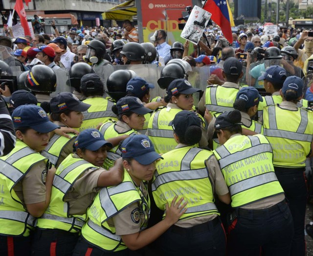 Opposition activists confront riot police during a protest against the government in Caracas on May 12, 2017. Daily clashes between demonstrators -who blame elected President Nicolas Maduro for an economic crisis that has caused food shortage- and security forces have left 38 people dead since April 1. Protesters demand early elections, accusing Maduro of repressing protesters and trying to install a dictatorship. / AFP PHOTO / FEDERICO PARRA