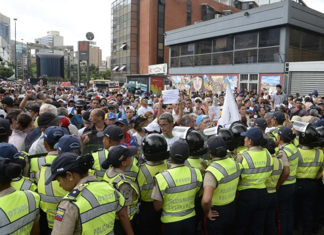 Opposition activists confront riot police during a protest against the government in Caracas on May 12, 2017. Daily clashes between demonstrators -who blame elected President Nicolas Maduro for an economic crisis that has caused food shortage- and security forces have left 38 people dead since April 1. Protesters demand early elections, accusing Maduro of repressing protesters and trying to install a dictatorship. / AFP PHOTO / FEDERICO PARRA
