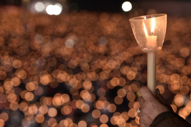 A pilgrim holds a candle at the Shrine of Fatima during the Blessing for the Candles from the Chapel of the Apparitions by Pope Francis, in Fatima on May 12, 2017. Two of the three child shepherds who reported apparitions of the Virgin Mary in Fatima, Portugal, one century ago, will be declared saints on May 13, 2017 by Pope Francis. The canonisation of Jacinta and Francisco Marto will take place during the Argentinian pontiff's visit to a Catholic shrine visited by millions of pilgrims every year. / AFP PHOTO / TIZIANA FABI