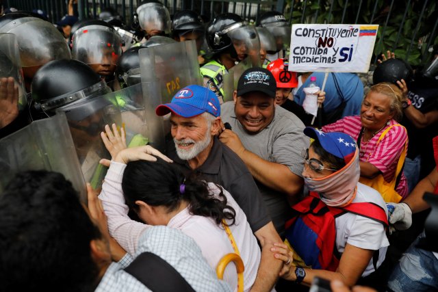Opposition supporters confront riot security forces with a sign that reads "No to constituent assembly, yes to food and medicines" while rallying against President Nicolas Maduro in Caracas, Venezuela, May 12, 2017. REUTERS/Carlos Garcia Rawlins
