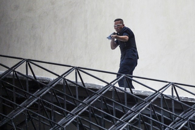 A man aims his weapon at demonstrators as they attack the administration headquarters of the Supreme Justice Court during riots following a protests against President Nicolas Maduro's government in Caracas, Venezuela, on June 7, 2017. The head of the Venezuelan military, General Vladimir Padrino Lopez, who is also President Nicolas Maduro's defence minister, is warning his troops not to commit "atrocities" against protesters demonstrating in the country's deadly political crisis. Tuesday's warning came after more than two months of violent clashes between protesters and security forces. The opposition and a press rights group say security forces have run over, attacked and robbed protesters and journalists. / AFP PHOTO / LUIS ROBAYO