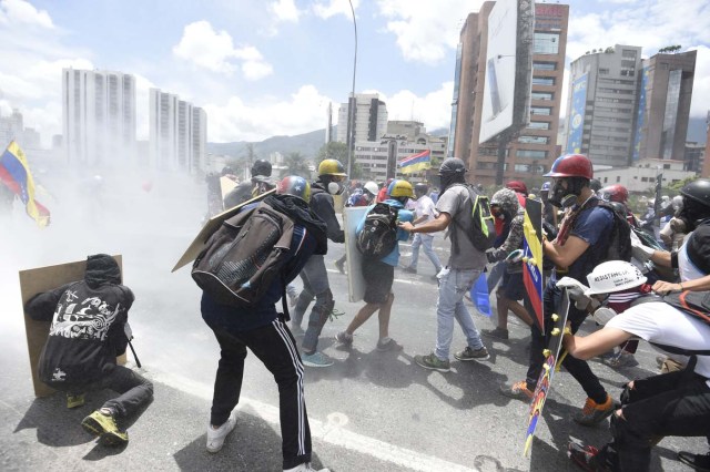 Opposition activists clash with riot police whilst protesting against the government of President Nicolas Maduro along the Francisco Fajardo motorway in Caracas on June 19, 2017. Venezuela's Supreme Court on Friday rejected a bid to put on trial several senior judges accused of favoring embattled President Nicolas Maduro as he clings to power in the face of deadly unrest. / AFP PHOTO / JUAN BARRETO