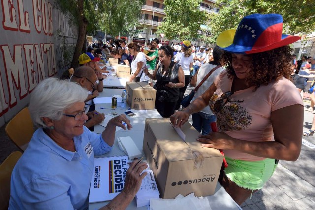 A Venezuelan resident in Barcelona casts her ballot during a symbolic plebiscite on president Maduro's project of a future constituent assembly, called by the Venezuelan opposition and held in Barcelona on July 16, 2017. / AFP PHOTO / LLUIS GENE
