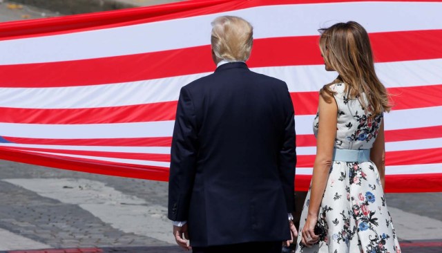 U.S. President Donald Trump and First Lady Melania Trump stand in front of the American flag at the end of the traditional Bastille Day military parade on the Champs-Elysees in Paris, France, July 14, 2017. REUTERS/Gonzalo Fuentes