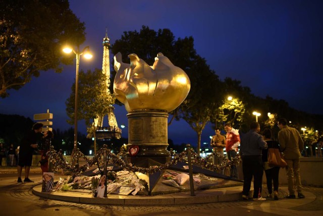 People pay their respects on August 30, 2017 over the Alma bridge at the Flame of Liberty monument - which became an unofficial memorial for Diana, Princess of Wales - in Paris, to mark the 20th anniversary of the death of Diana who died in a car crash in a nearby tunnel on August 31, 1997. The Eiffel tower is seen in the background. The life of Diana -- a shy, teenage aristocrat who suddenly became the world's most famous woman -- and her tragic death at 36 still captivates millions across the globe. Diana died in a car crash in Paris in the early hours of August 31, 1997, along with Dodi Fayed, her wealthy Egyptian film producer boyfriend of two months, and a drink-impaired, speeding driver Henri Paul, who was trying to evade paparazzi. / AFP PHOTO / Eric FEFERBERG