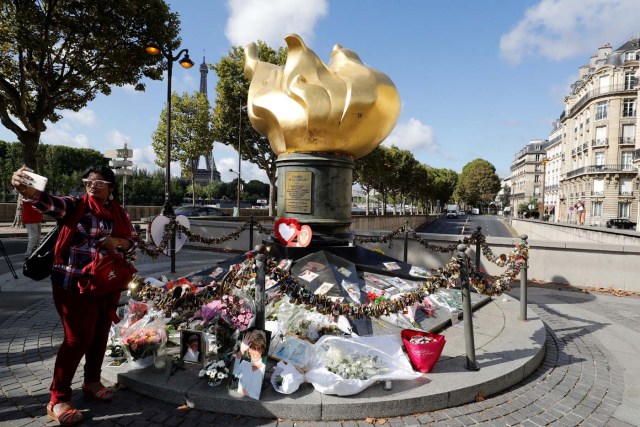 A woman takes a selfie next to the Flame of Liberty monument - which became an unofficial memorial for Diana, Princess of Wales who died in a car crash in a nearby tunnel - adorned with flowers, messages, pictures and locks, over the Alma bridge in Paris on August 31, 2017, on the 20th anniversary of the death of the Princess. The life of Diana -- a shy, teenage aristocrat who suddenly became the world's most famous woman -- and her tragic death at 36 still captivates millions across the globe. Diana died in a car crash in Paris in the early hours of August 31, 1997, along with Dodi Fayed, her wealthy Egyptian film producer boyfriend of two months, and a drink-impaired, speeding driver Henri Paul, who was trying to evade paparazzi. / AFP PHOTO / Patrick KOVARIK