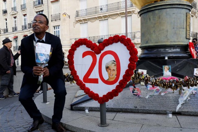 A man sits next to a heat-shaped sign marking the 20th anniversary of the death of the Princess Diana at the Flame of Liberty monument - which became an unofficial memorial for the Princess of Wales who died in a car crash in a nearby tunnel - over the Alma bridge in Paris on August 31, 2017. The life of Diana -- a shy, teenage aristocrat who suddenly became the world's most famous woman -- and her tragic death at 36 still captivates millions across the globe. Diana died in a car crash in Paris in the early hours of August 31, 1997, along with Dodi Fayed, her wealthy Egyptian film producer boyfriend of two months, and a drink-impaired, speeding driver Henri Paul, who was trying to evade paparazzi. / AFP PHOTO / Patrick KOVARIK
