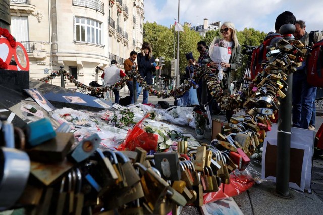 People look at flowers, messages, pictures and locks laid around the Flame of Liberty monument - which became an unofficial memorial for Diana, Princess of Wales who died in a car crash in a nearby tunnel - over the Alma bridge in Paris on August 31, 2017, on the 20th anniversary of the death of the Princess. The life of Diana -- a shy, teenage aristocrat who suddenly became the world's most famous woman -- and her tragic death at 36 still captivates millions across the globe. Diana died in a car crash in Paris in the early hours of August 31, 1997, along with Dodi Fayed, her wealthy Egyptian film producer boyfriend of two months, and a drink-impaired, speeding driver Henri Paul, who was trying to evade paparazzi. / AFP PHOTO / Patrick KOVARIK