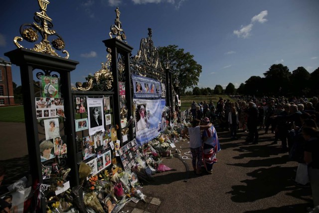 Members of the public gather at the tributes of flowers, candles and photographs outside one of the gates of Kensington Palace in London on August 31, 2017, to mark the 20th anniversary of the death of Diana, Princess of Wales. Tributes of photographs, candels and photographs have gathered at the gates of Kensington Palace left by well-wishers and fans of Diana, princess of Wales to mark the 20th anniversary of her death on August 31, 2017. The Princess of Wales died in a fatal car crash in Paris on August 31, 1997. Well-wishers and fans of Diana visited the palace in the early hours of the morning on August 31 to pay their respects with a vigil at the famous gates of Diana's former residence. / AFP PHOTO / Daniel LEAL-OLIVAS