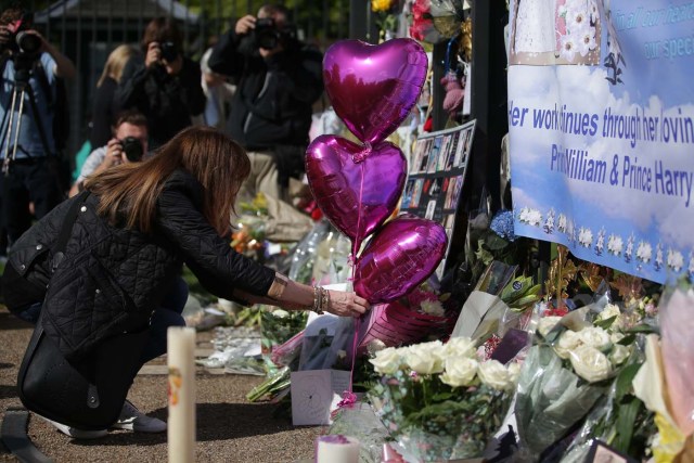 A woman pauses at the tributes of flowers, candles and photographs outside one of the gates of Kensington Palace in London on August 31, 2017, to mark the 20th anniversary of the death of Diana, Princess of Wales. Tributes of photographs, candels and photographs have gathered at the gates of Kensington Palace left by well-wishers and fans of Diana, princess of Wales to mark the 20th anniversary of her death on August 31, 2017. The Princess of Wales died in a fatal car crash in Paris on August 31, 1997. Well-wishers and fans of Diana visited the palace in the early hours of the morning on August 31 to pay their respects with a vigil at the famous gates of Diana's former residence. / AFP PHOTO / Daniel LEAL-OLIVAS