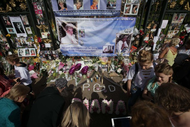 Members of the public gather at the tributes of flowers, candles and photographs outside one of the gates of Kensington Palace in London on August 31, 2017, to mark the 20th anniversary of the death of Diana, Princess of Wales. Fans and friends of Diana, Princess of Wales, were marking 20 years since her death on August 31, 2017 as the nation looked back on the day when the shocking news broke she had been killed in a late-night Paris car crash. / AFP PHOTO / Daniel LEAL-OLIVAS