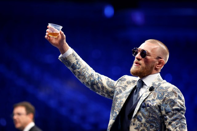 UFC lightweight champion Conor McGregor of Ireland raises a cup of Irish whiskey during post-fight news conference at T-Mobile Arena in Las Vegas, Nevada, U.S. August 27, 2017. REUTERS/Steve Marcus