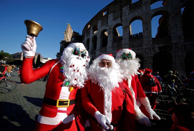 People pose as more than a hundred cyclists dressed as Santa Claus meet at the Colosseum in Rome, Italy December 17, 2017. REUTERS/Tony Gentile