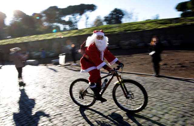 A man rides a bike as more than a hundred cyclists dressed as Santa Claus meet at the Colosseum in Rome, Italy December 17, 2017. REUTERS/Tony Gentile