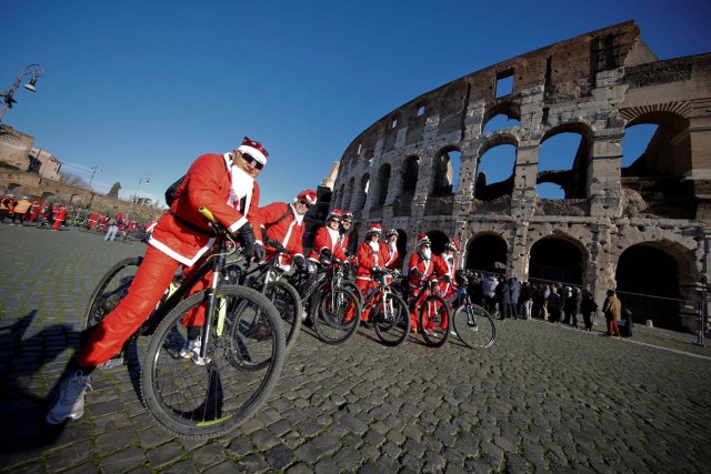 People pose as more than a hundred cyclists dressed as Santa Claus meet at the Colosseum in Rome, Italy December 17, 2017. REUTERS/Tony Gentile