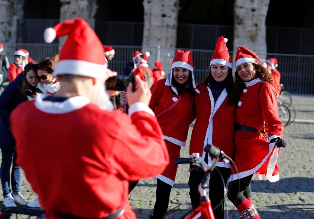 Women pose as more than a hundred cyclists dressed as Santa Claus meet at the Colosseum in Rome, Italy December 17, 2017. REUTERS/Tony Gentile