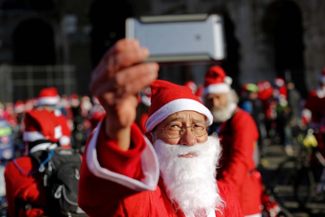 A man takes a selfie as more than a hundred cyclists dressed as Santa Claus meet at the Colosseum in Rome, Italy December 17, 2017. REUTERS/Tony Gentile