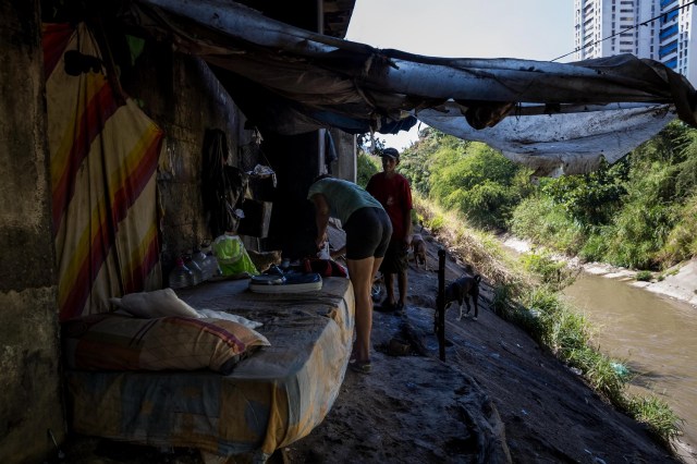 Fotografía del 22 de diciembre de 2017 de hombres en el Río Guaire debajo de un puente, en la ciudad de Caracas (Venezuela). La severa crisis económica y social de Venezuela ha modificado los paisajes de la capital, no solo por la existencia de ciudadanos que buscan comida en la basura, sino también por la presencia de personas que han tomado los puentes como lugares de abrigo, algunos ya habitados por antiguos residentes. EFE/MIGUEL GUTIÉRREZ