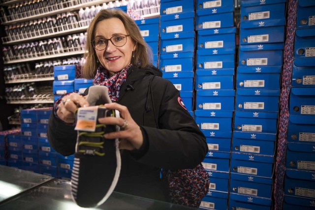 Leader of the BVG, Berlins´s public transport network, Sigrid Nikutta poses with a pair of sneakers with a public transport ticket as people queued up to buy the Adidas / BVG (Berlin Transport) trainers at the Overkill shoe store in Berlin on January 16, 2018.   The shoes, set to cost 180 euro and only 500 available, sporting the camouflage design of the bus and underground seats also grant the wearer access to the use of Berlin's public transport for a year. / AFP PHOTO / Odd ANDERSEN