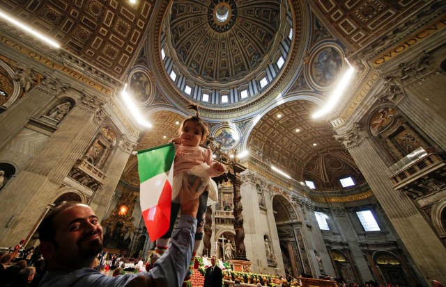 A migrant holds his child waving an Italian flag as Pope Francis leads a special mass to mark International Migrants Day in Saint Peter's Basilica at the Vatican January 14, 2018. REUTERS/Max Rossi